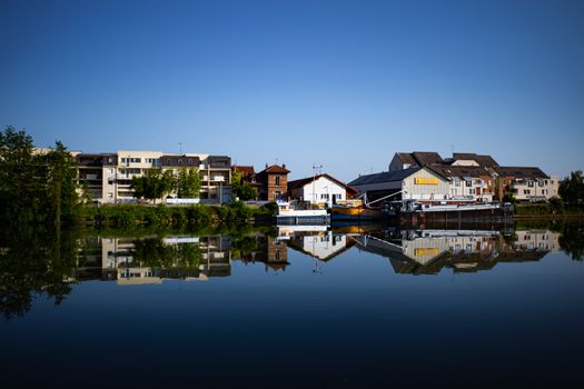 Tranquil scene of buildings reflecting on a lake in Compiègne, France.