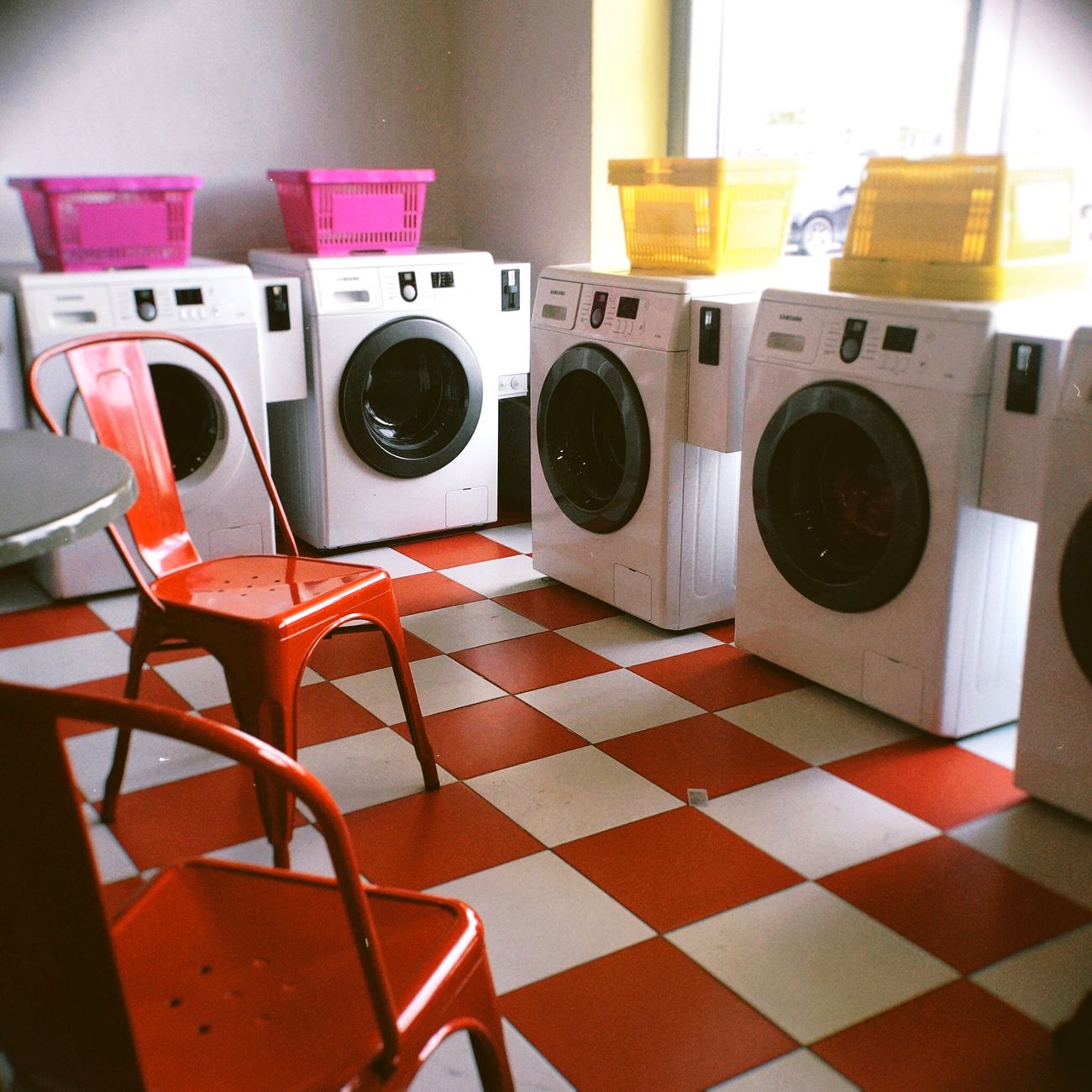 Bright laundry room with red checkered floor and colorful baskets, offering a modern look.