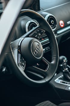 Close-up of a luxury Audi car interior focusing on the steering wheel and dashboard.
