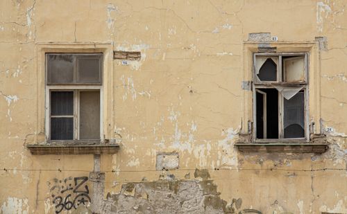 Free Weathered wall with peeling yellow paint and deteriorated windows, Bratislava. Stock Photo