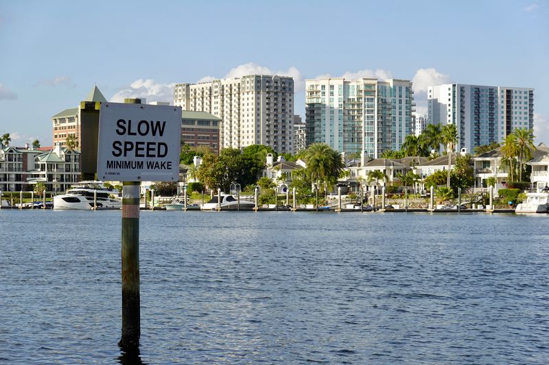 A picturesque view of downtown Tampa's waterfront with a 'Slow Speed' sign and modern buildings in the background.