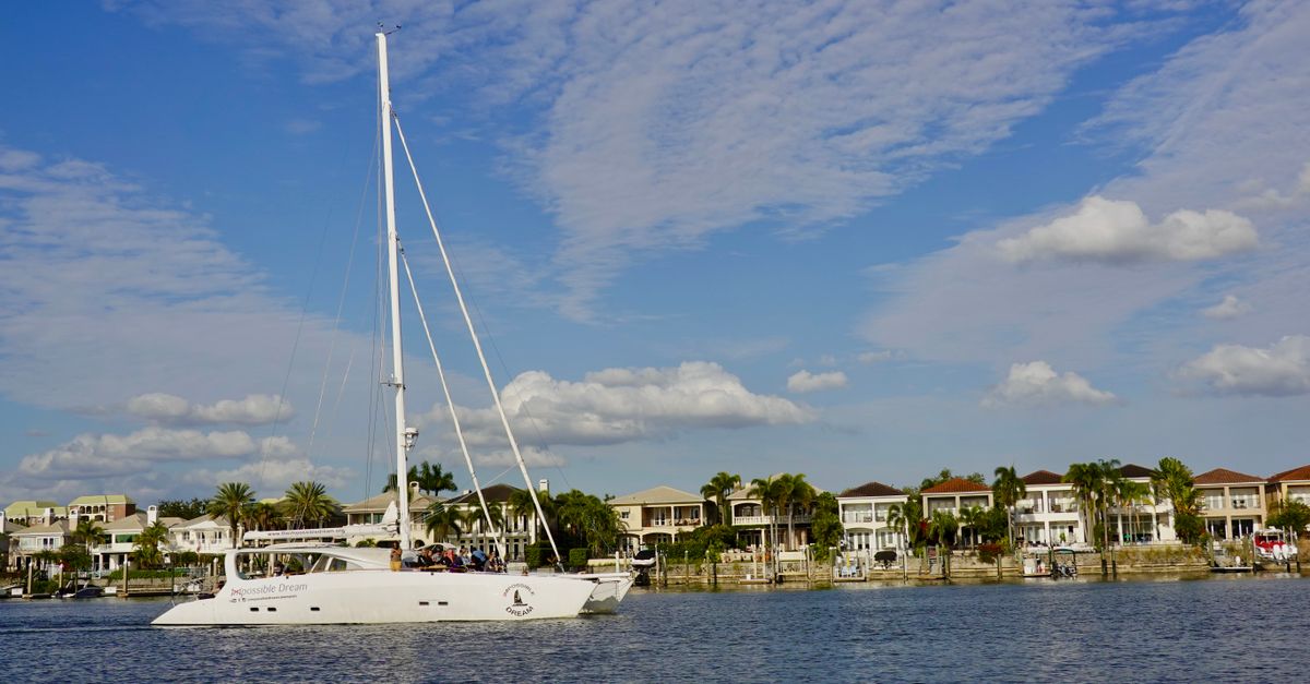 Yacht cruising in scenic Tampa Bay with waterfront homes and clear skies.