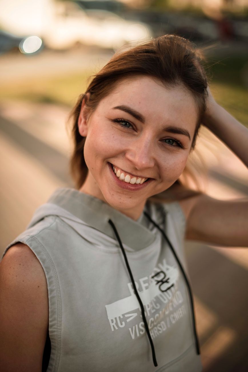 Vibrant portrait of a smiling young woman outdoors during golden hour.
