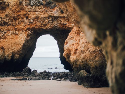 Free Stunning rock formation with a natural arch opening to a serene ocean landscape. Stock Photo