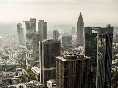 Aerial view of Frankfurt's skyscraper-filled skyline under a hazy sky.
