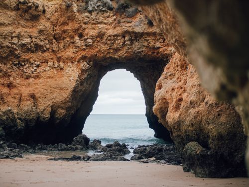 Free A breathtaking view through a natural coastal rock archway leading to the open sea. Stock Photo