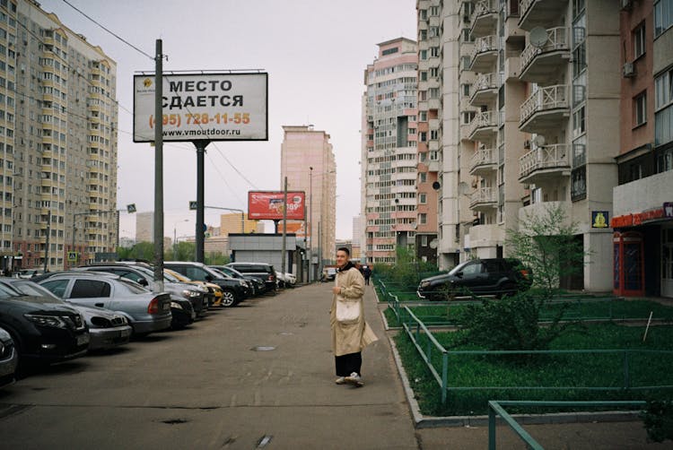 Man Wearing Beige Overcoat Standing Near Parked Cars 