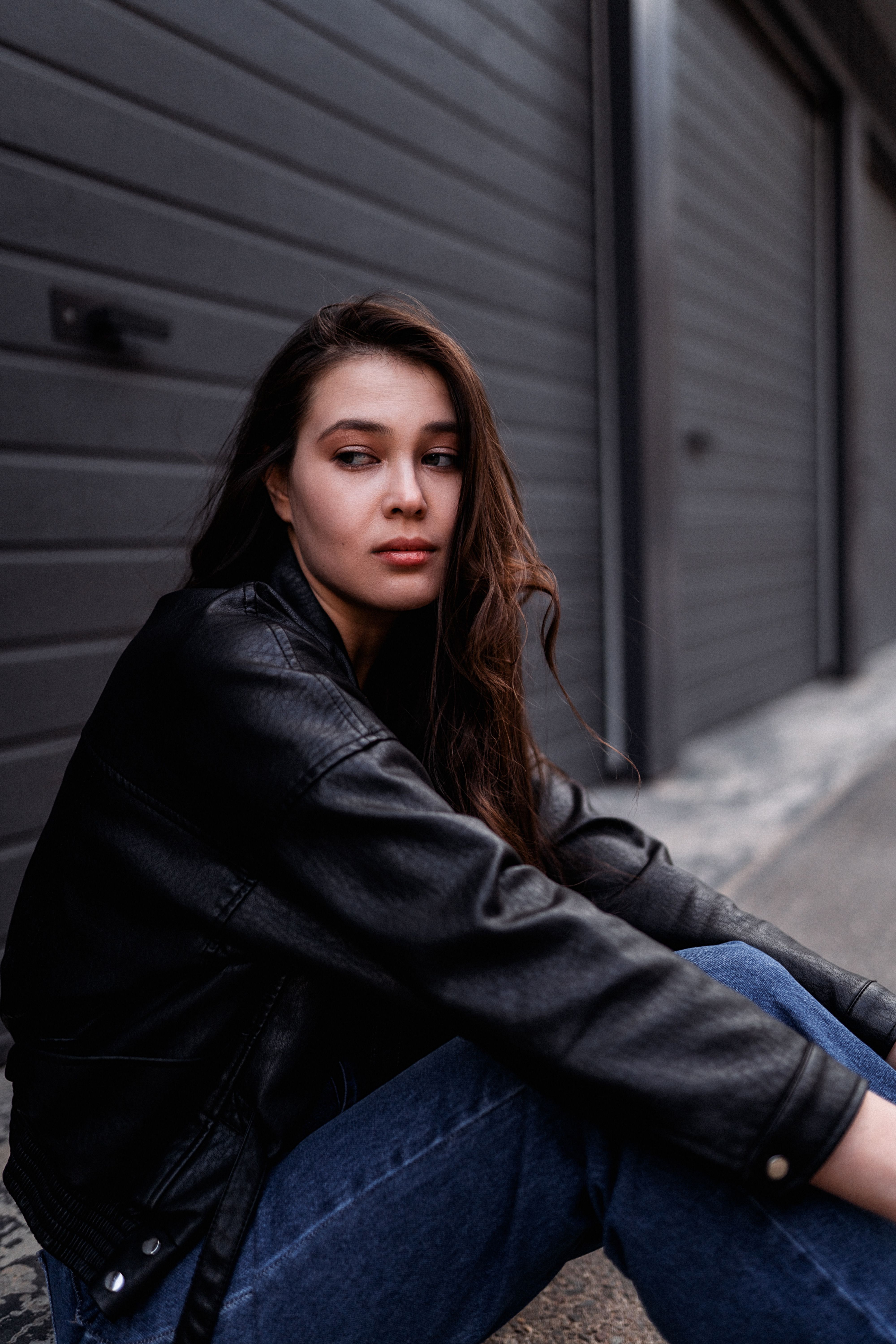 Woman in Black Leather Jacket and Blue Denim Jeans Sitting on Gray ...