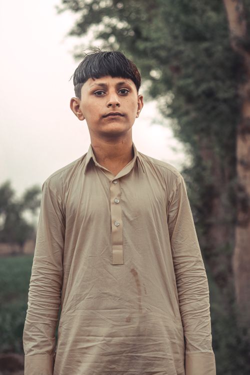 Free Young boy standing outdoors in casual attire with blurred natural background. Stock Photo