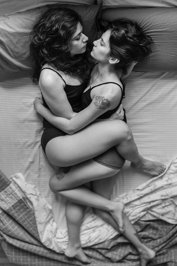 Women Lying In Bed In Intimate Embrace