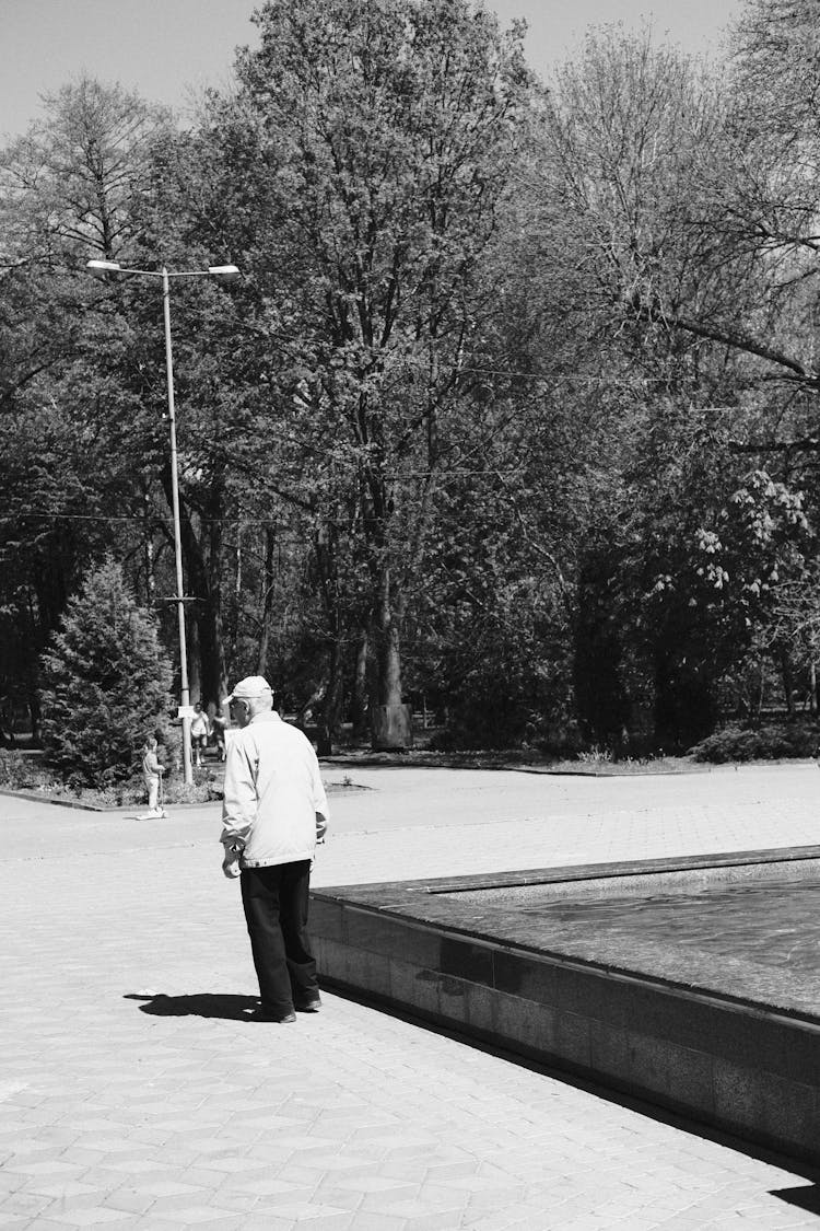 Black And White Photo Of A Elderly Man Walking On A Park