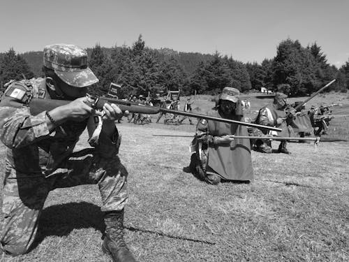 Grayscale Photo of Men Holding Rifles and Weapons