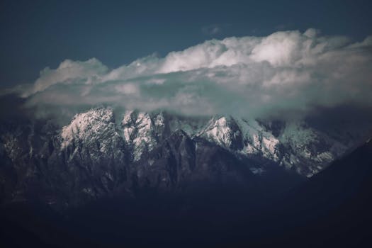 A breathtaking view of snow-capped mountains shrouded in clouds, capturing the serene beauty of nature.