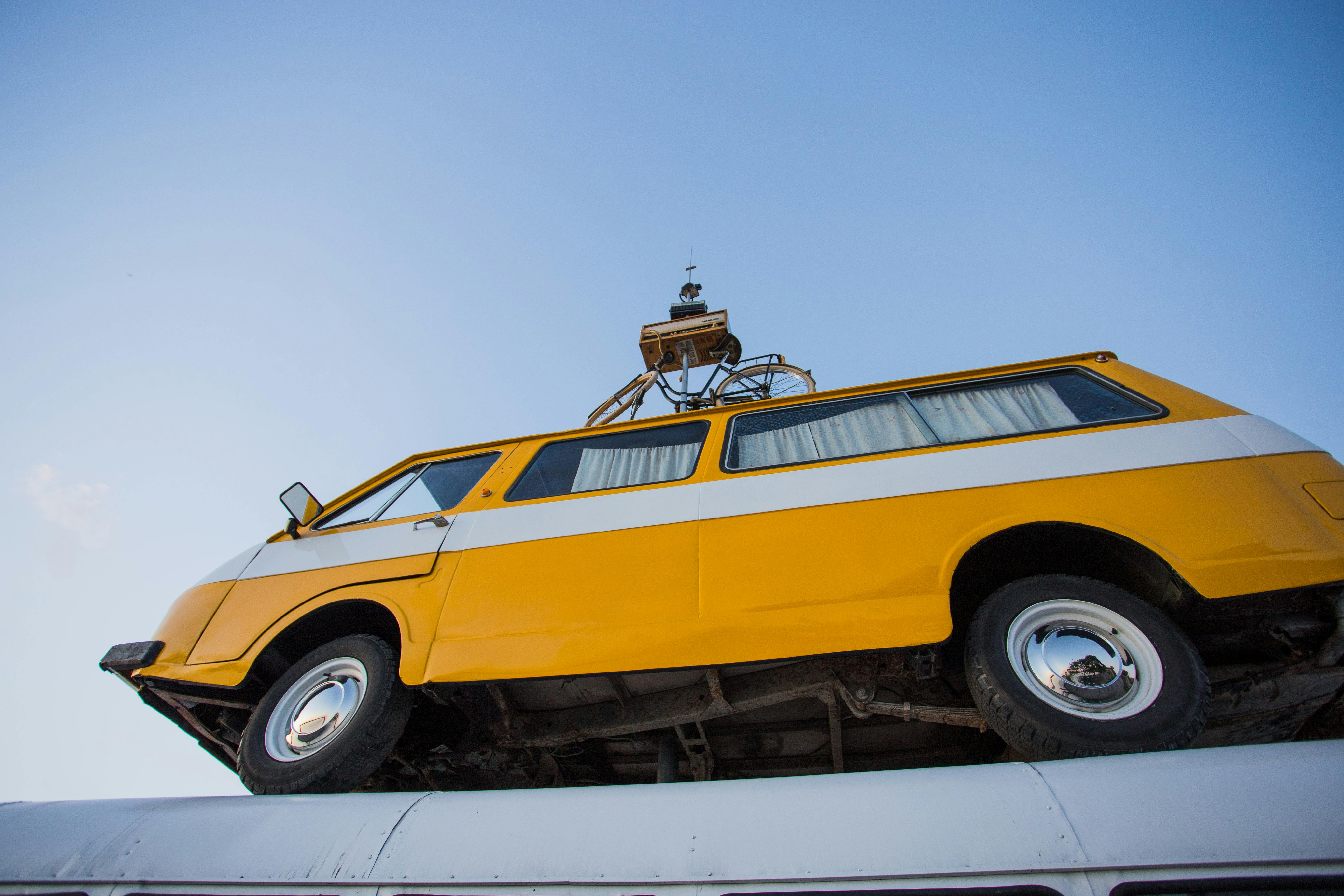 从独特的角度拍摄，一辆黄色老式货车安装在屋顶上，映衬着清澈的蓝天