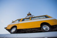 从独特的角度拍摄，一辆黄色老式货车安装在屋顶上，映衬着清澈的蓝天