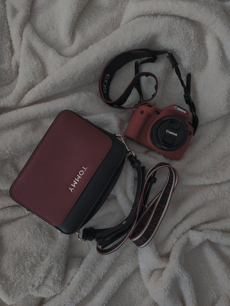 Red Canon Camera Beside The Tommy Sling Bag 