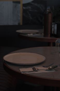 A simple dining arrangement featuring a white plate and silver cutlery on a round table.