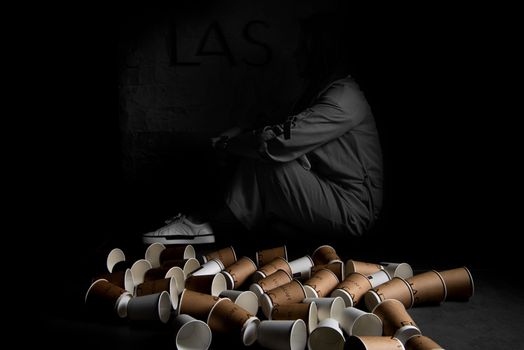 Person Sitting Beside Empty Paper Cups on Floor 