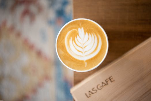 Top view of a beautifully crafted latte with leaf art, set against a blurred wooden table.