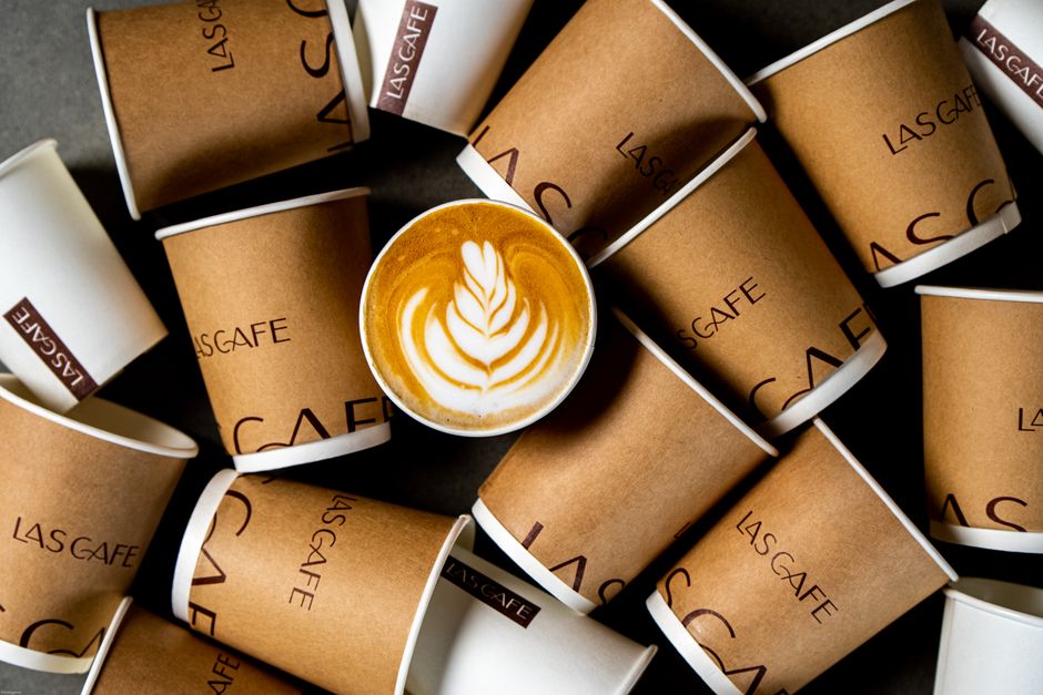 Top view of latte art coffee surrounded by Las Cafe paper cups. Perfect for beverage and cafe themes.