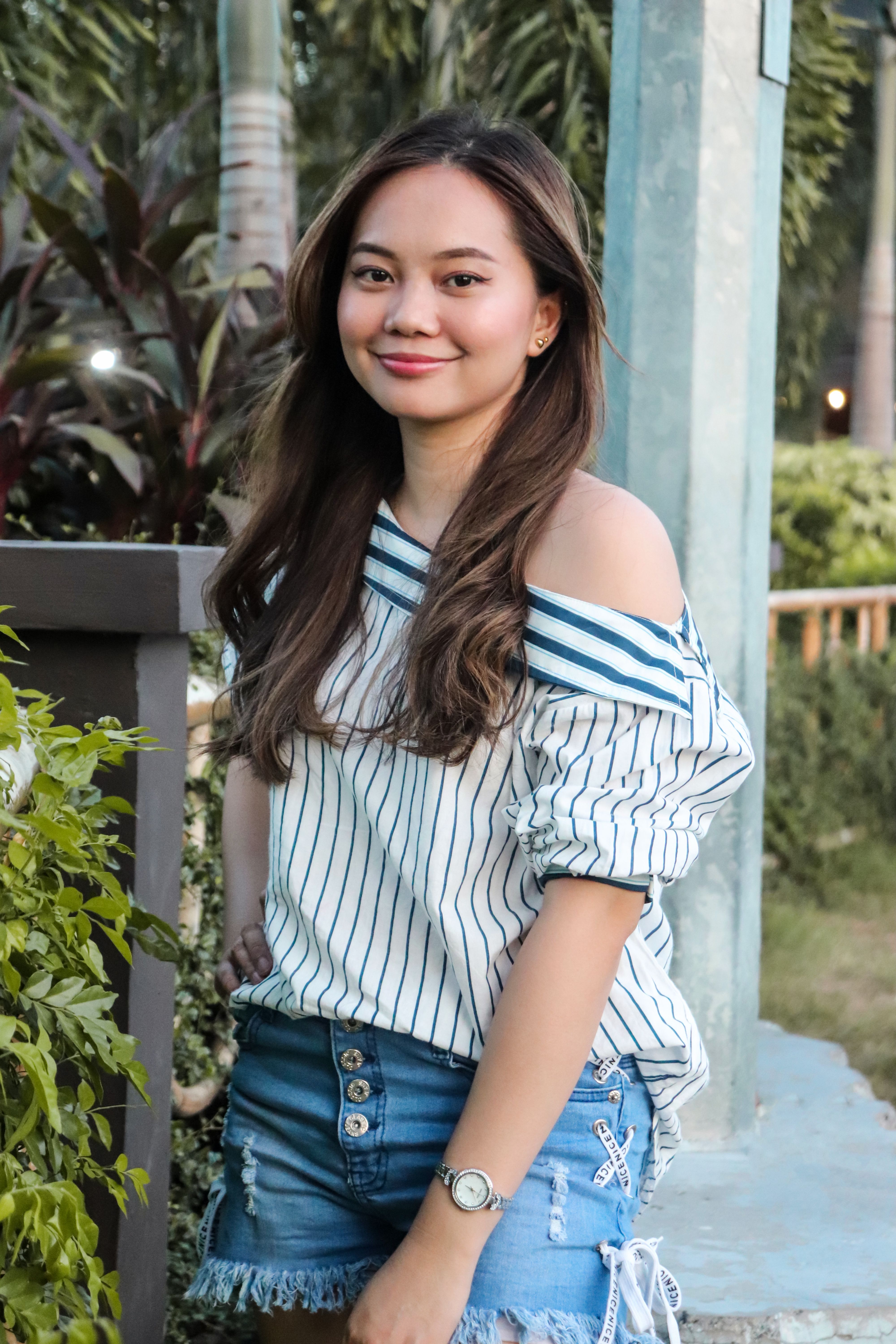 Young woman in denim shorts smiling confidently outdoors in Taguig.