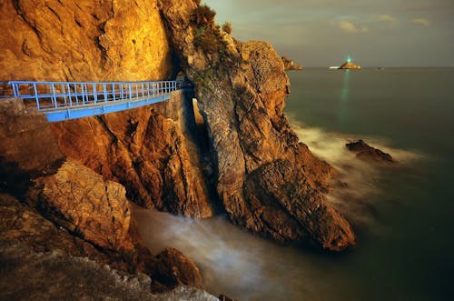 Blue Bridge on a Rock Mountain Near Body of Water