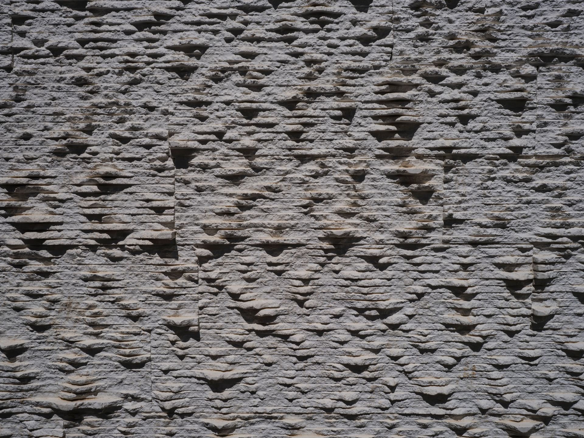 Rough textured stone wall surface perfect for architectural backdrop.