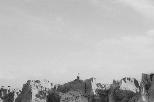 Minimalist black and white landscape of a person standing on rocks in Canoa Quebrada, Brazil.