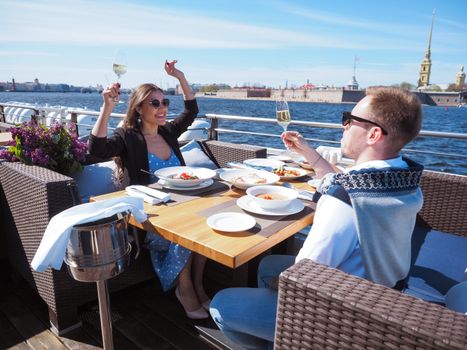 Couple enjoying a romantic meal on a boat cruise with a scenic view.