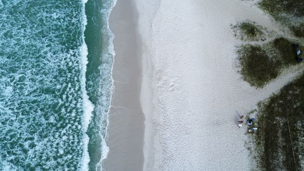 Aerial shot of a beach with waves crashing on white sand, showcasing nature's beauty.