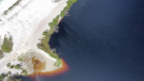 Free Drone shot capturing the contrast of white sand and deep blue ocean on a sunny day. Stock Photo