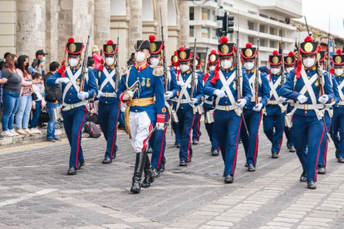Free Masked soldiers marching in a parade on a street in Ecuador, showcasing ceremonial uniforms. Stock Photo