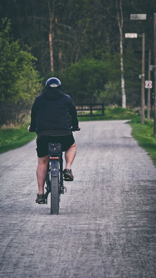 Free A Man in Black Jacket and Shorts Riding a Bicycle Stock Photo