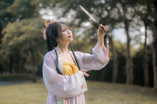 A Woman Wearing White and Pink Robe Holding a Hand Fan