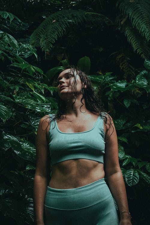 Woman in Teal Sports Bra Standing Beside Green Plants