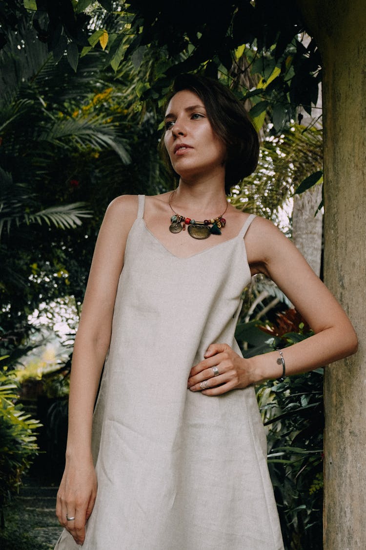 Woman In Loose Fitting Dress Standing In Front Of Green Trees