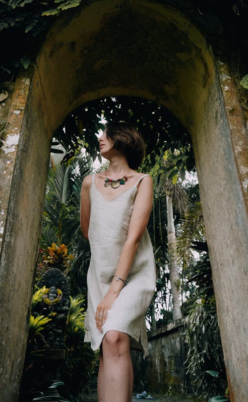 Woman Wearing a Sleeveless Beige Dress Standing under an Arch