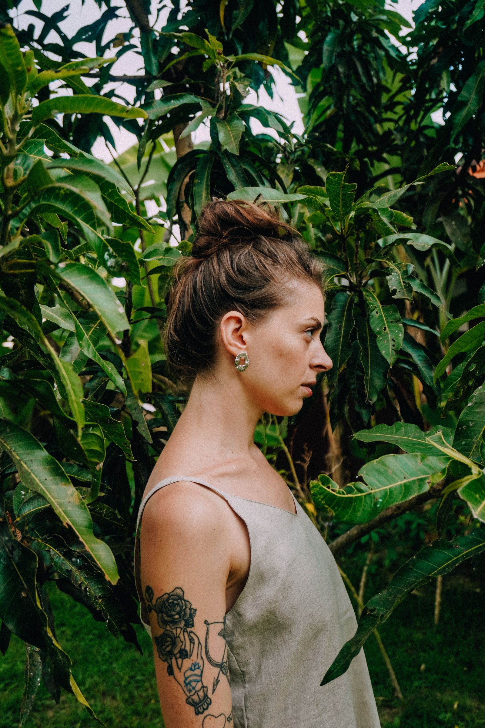 Woman in loose linen dress among green foliage