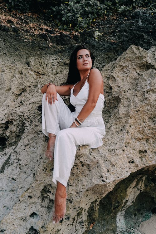 Woman in White Suit Sitting on Rocks