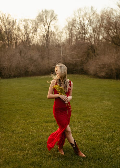 Woman in Red Sleeveless Dress Standing on Green Grass Field