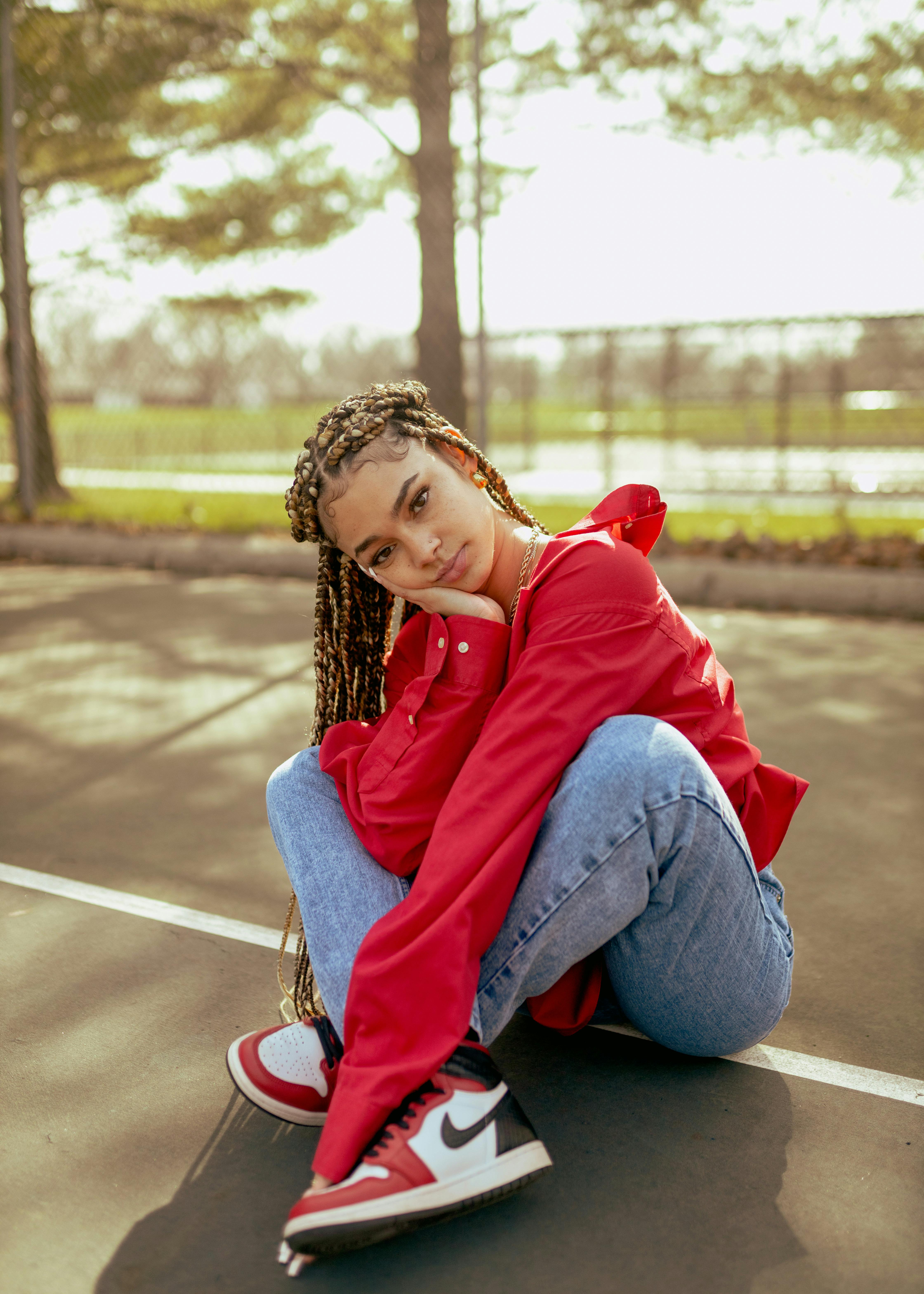 model girl with many pigtails sitting cross legged on road