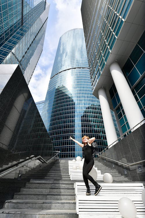 Woman Posing on Stairs near Skyscrapers