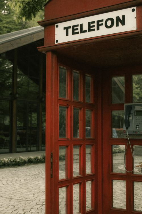 Free Charming red telephone booth in a tranquil outdoor location, evoking nostalgia and retro vibes. Stock Photo