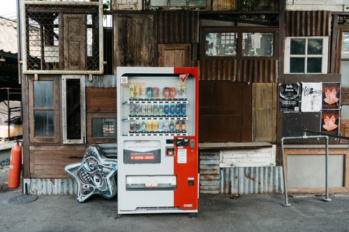 Free A vending machine stands in front of an eclectic wall with corrugated metal and old wood panels. Stock Photo
