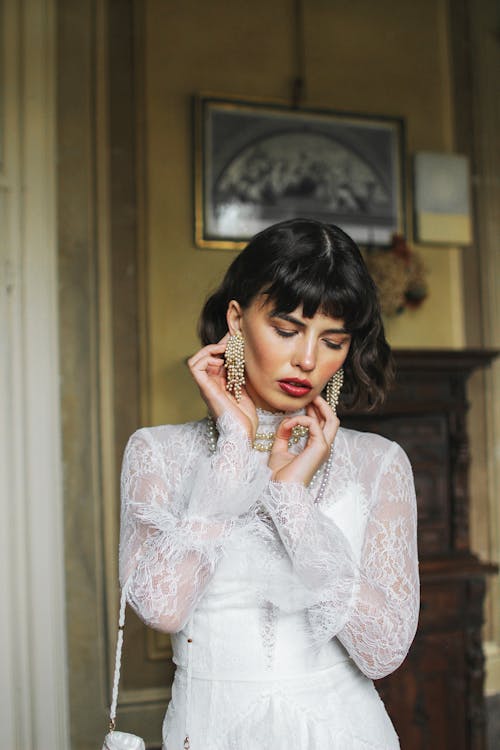 Woman in White Dress Touching her Face and Earrings