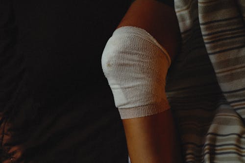Free Person with Medical Gauze Bandage on Injured Knee Stock Photo