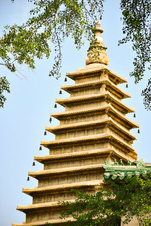 Free A beautiful historic pagoda framed by lush green trees under a clear blue sky. Stock Photo
