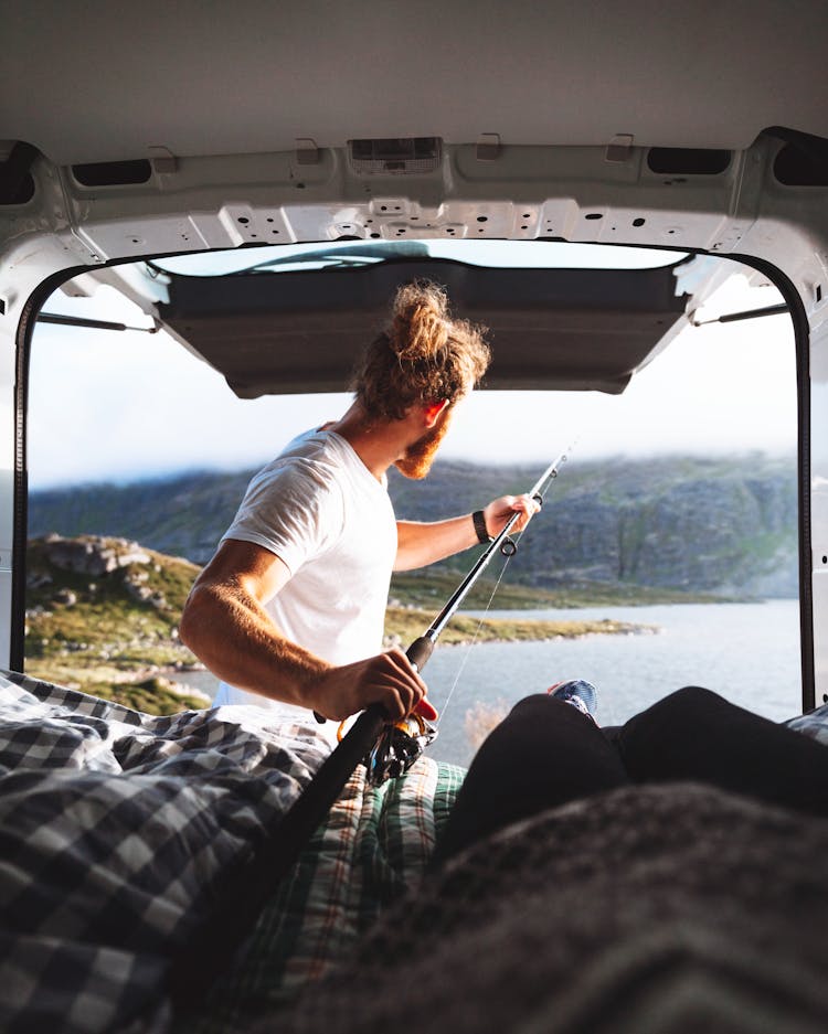 Man With A Beard Fishing Out Of A Camping Van