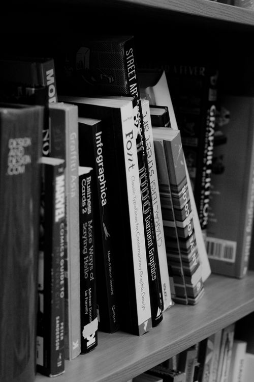 Free A monochrome shot of a bookshelf filled with various books focusing on design and graphics. Stock Photo