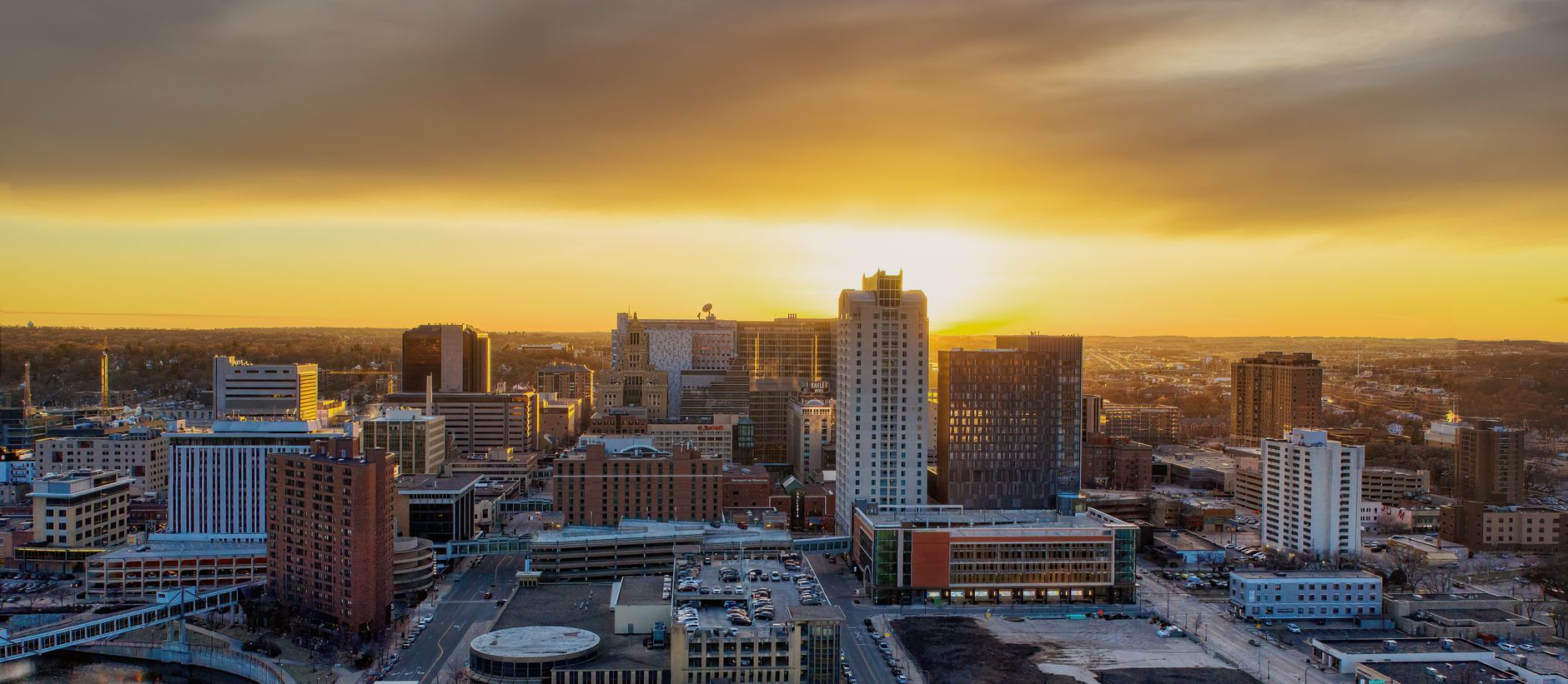 Aerial view of Rochester, MN cityscape with a vibrant sunset in the background.